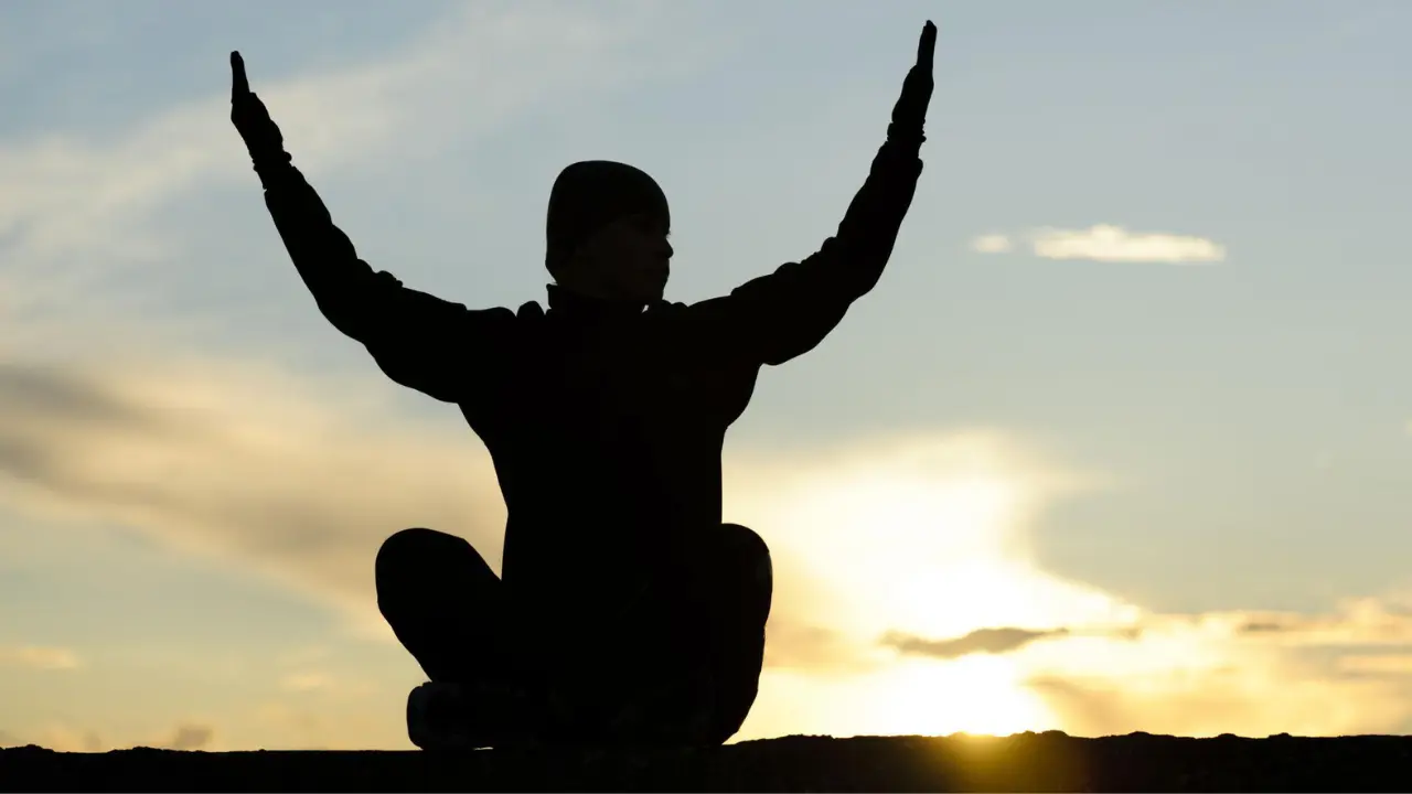 Person reflecting at sunrise with Bible, representing the question of why God made us and the search for purpose